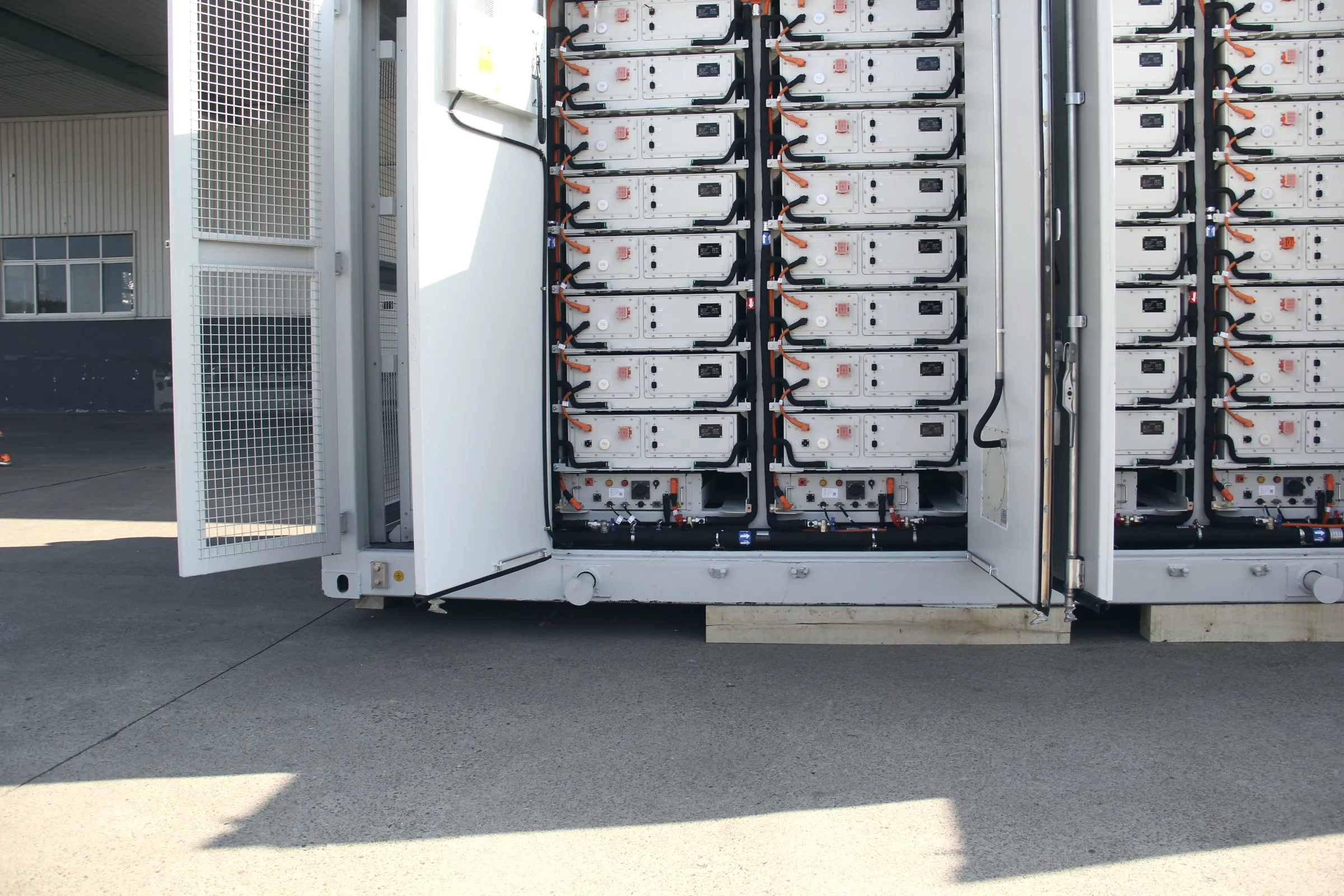 Technician beside a 5 MWh BESS container before shipment
