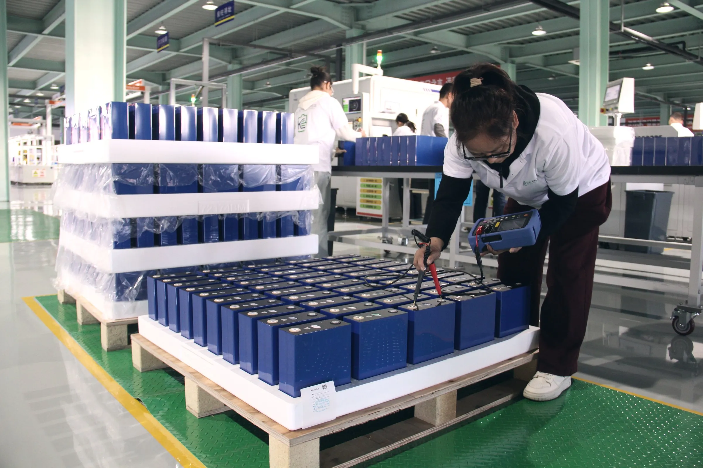 Operatrice che misura celle LFP su un pallet nell'area di ricevimento