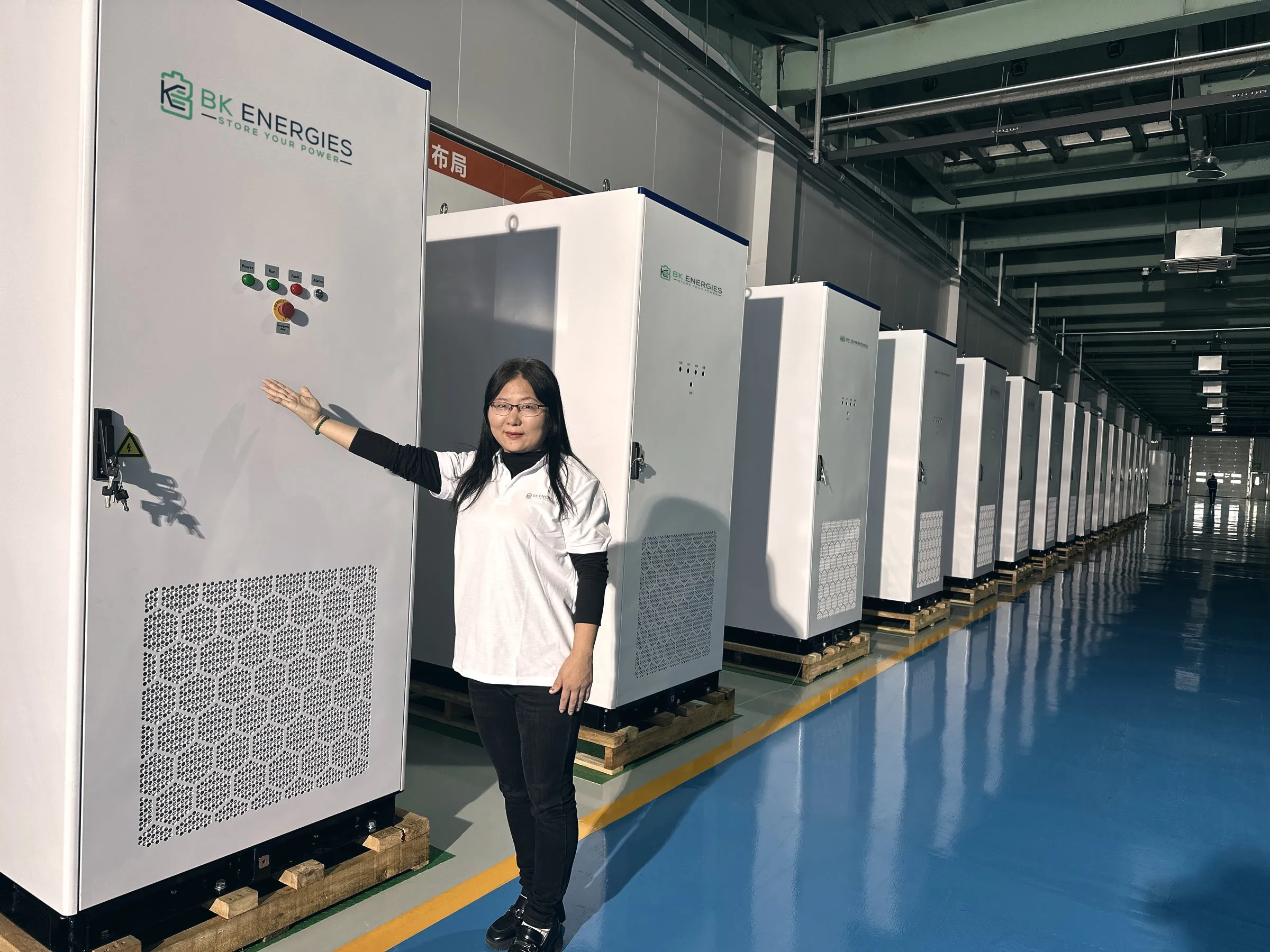 Técnica de BK Energies señalando una línea de equipos Power Pro en la nave de integración